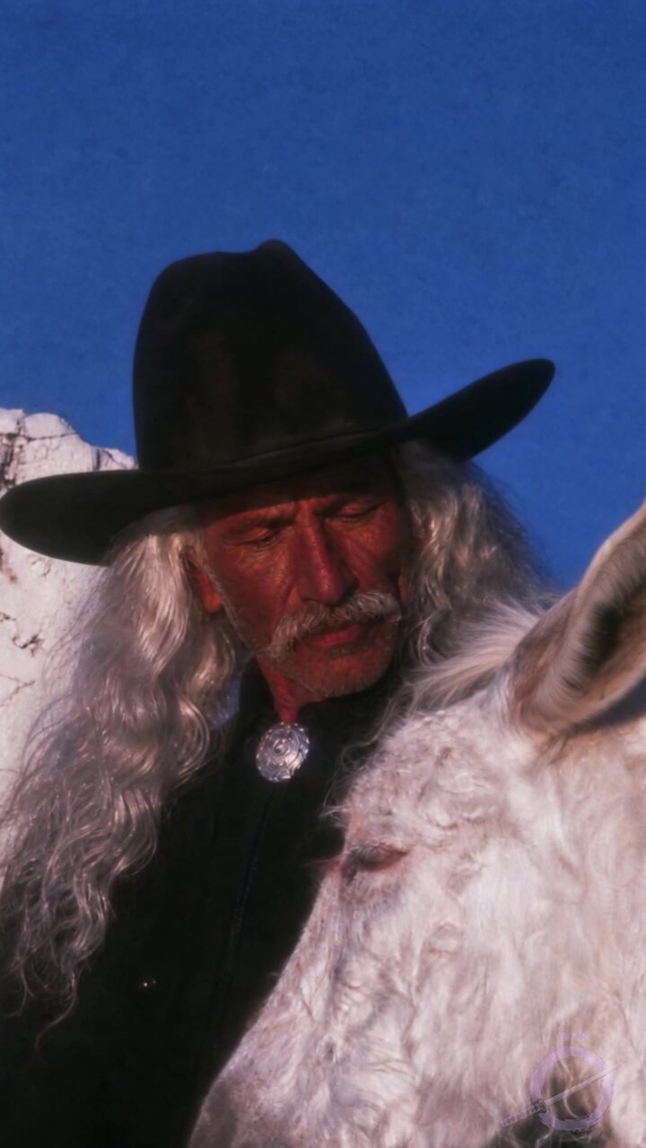El Patrón con sombrero negro y caballo blanco